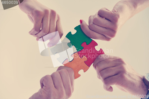 Image of Group of business people assembling jigsaw puzzle