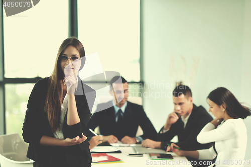 Image of business woman with her staff in background at office