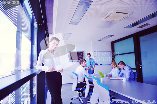 Image of business woman with her staff in background at office