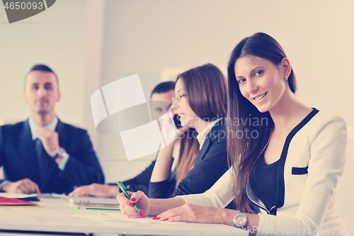 Image of business woman with her staff in background at office