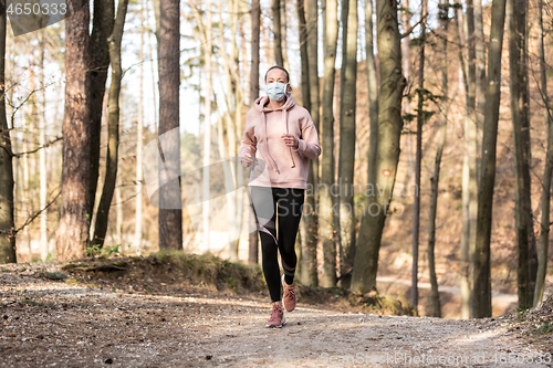 Image of Corona virus, or Covid-19, is spreading all over the world. Portrait of caucasian sporty woman wearing a medical protection face mask while running in nature.