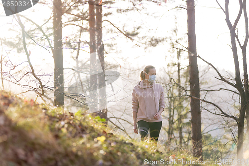 Image of Corona virus, or Covid-19, is spreading all over the world. Portrait of caucasian sporty woman wearing a medical protection face mask while walking in the forest. Corona virus.