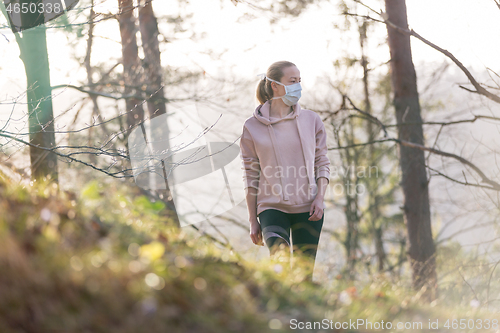 Image of Corona virus, or Covid-19, is spreading all over the world. Portrait of caucasian sporty woman wearing a medical protection face mask while walking in the forest. Corona virus.