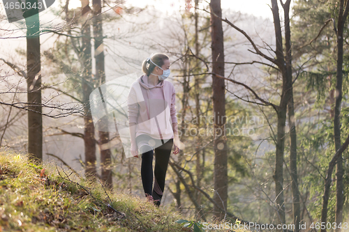 Image of Corona virus, or Covid-19, is spreading all over the world. Portrait of caucasian sporty woman wearing a medical protection face mask while walking in the forest. Corona virus.