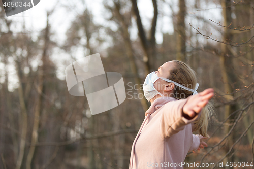 Image of Portrait of caucasian sporty woman wearing medical protection face mask while relaxing by taking a deep breath in forest. Corona virus, or Covid-19, is spreading all over the world