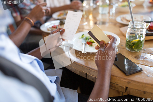 Image of hands holding bill and credit card at restaurant