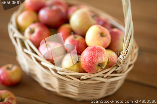 Image of ripe apples in wicker basket on wooden table