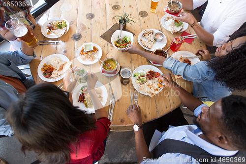 Image of international friends eating at restaurant