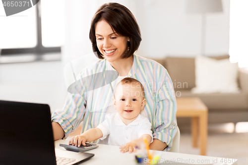 Image of working mother with baby boy and laptop at home