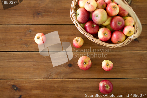 Image of ripe apples in wicker basket on wooden table