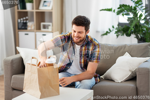 Image of smiling man unpacking takeaway food at home