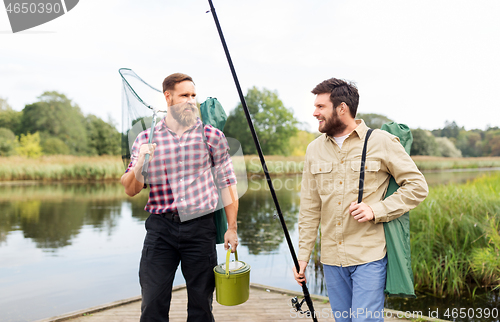 Image of male friends with net and fishing rods on lake