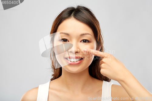 Image of happy smiling young asian woman touching her face