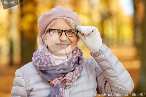 Image of portrait of happy senior woman at autumn park