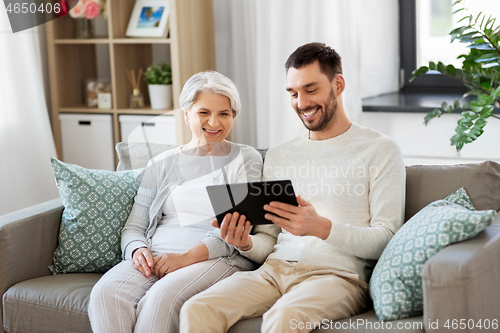 Image of old mother and adult son with tablet pc at home