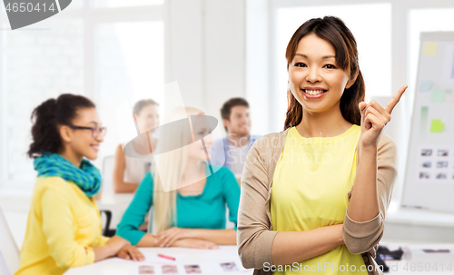 Image of happy asian woman pointing finger up