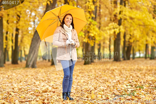 Image of happy woman with umbrella in autumn park