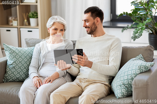 Image of old mother and adult son with tablet pc at home