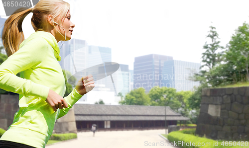 Image of woman with earphones running at city park