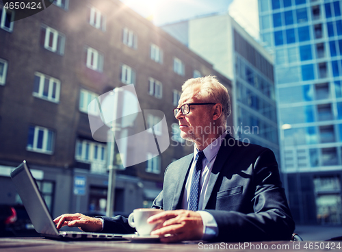 Image of senior businessman with laptop drinking coffee