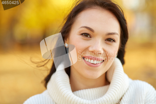 Image of portrait of happy young woman in autumn park