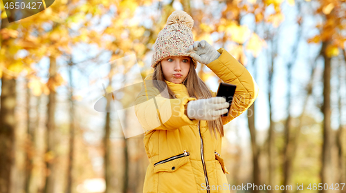 Image of girl taking selfie by smartphone at autumn park