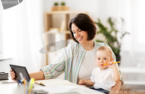 Image of working mother with tablet pc and baby at home