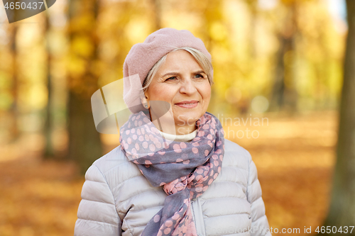 Image of portrait of happy senior woman at autumn park