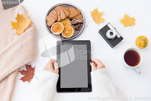 Image of hands with tablet pc, tea and autumn leaves