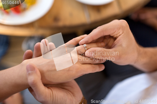 Image of man giving diamond ring to woman at restaurant