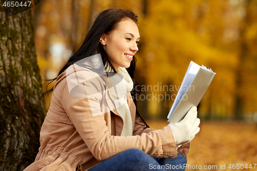Image of woman reading book at autumn park