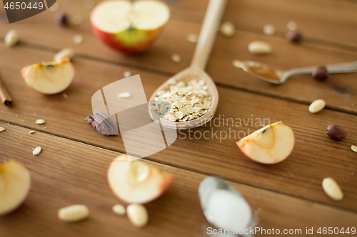 Image of oatmeal in wooden spoon, cut apples and nuts