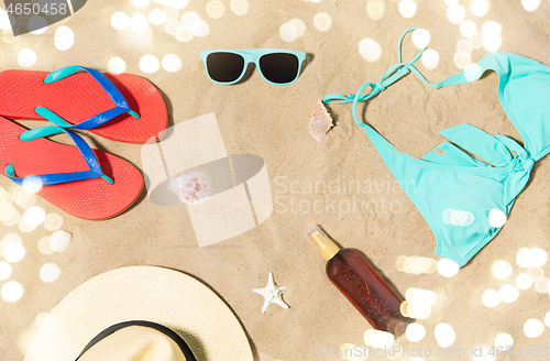 Image of straw hat, flip flops and sunglasses on beach sand