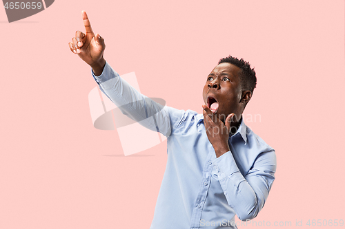 Image of The young attractive man looking suprised isolated on pink