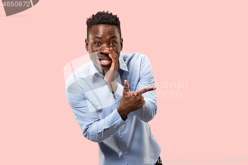 Image of The young man whispering a secret behind her hand over pink background