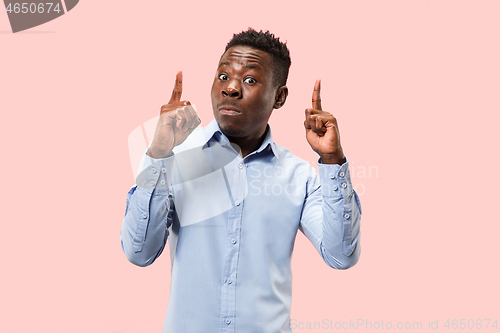 Image of The young attractive man looking suprised isolated on pink