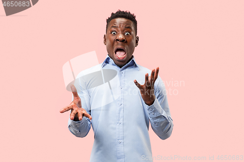 Image of The young attractive man looking suprised isolated on pink