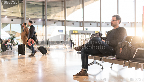 Image of Casual young male using her cell phone while waiting to board a plane at airport departure gates.