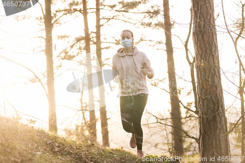 Image of Corona virus, or Covid-19, is spreading all over the world. Portrait of caucasian sporty woman wearing a medical protection face mask while running in nature.