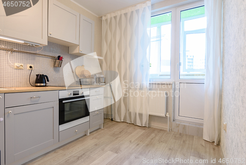 Image of Kitchen interior in the apartment. Exit to the balcony and large windows.