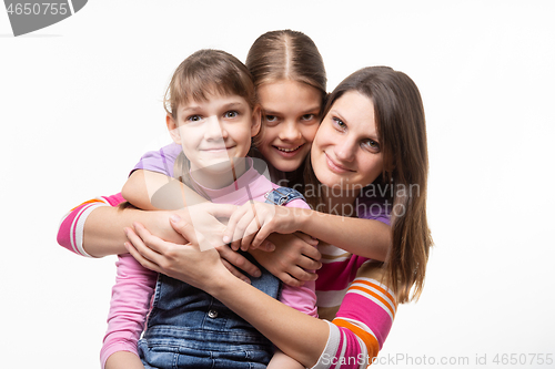 Image of Two girls and a mother of European appearance happily look at the frame