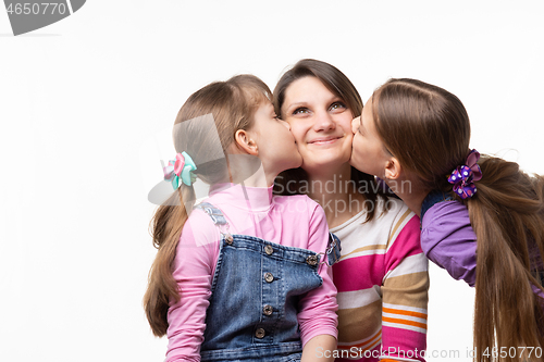 Image of Two sisters kiss mom on the cheek, mom joyfully looks up