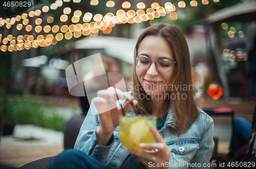Image of Woman with cocktail at cafe outdoor.