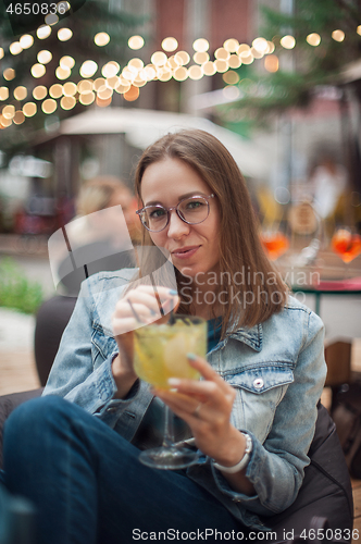 Image of Woman with cocktail at cafe outdoor.