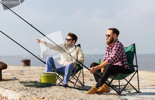 Image of male friends with fishing rods on pier