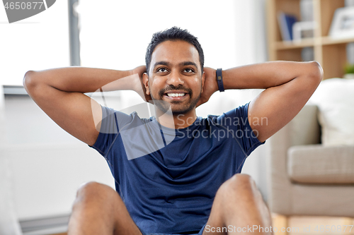 Image of indian man making abdominal exercises at home