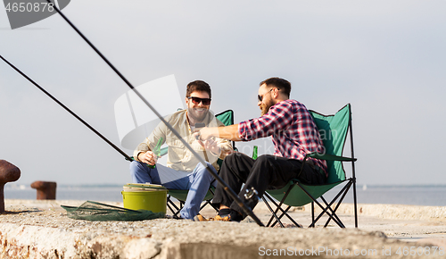 Image of friends with smartphone fishing and drinking beer