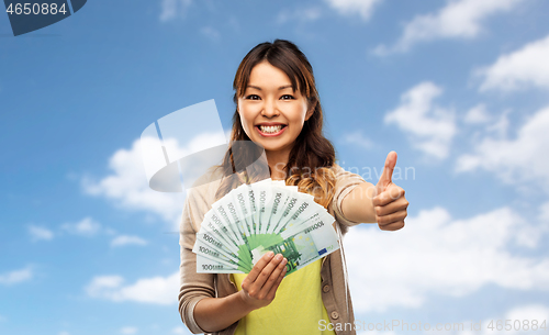 Image of asian woman with euro money showing thumbs up