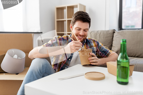 Image of smiling man eating takeaway food at new home