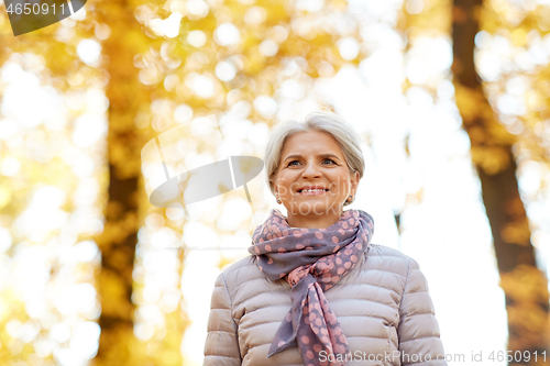 Image of portrait of happy senior woman at autumn park